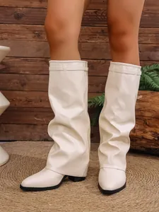 Detailed view of cream-colored slouchy pant boots featuring a pointed toe and chunky heel