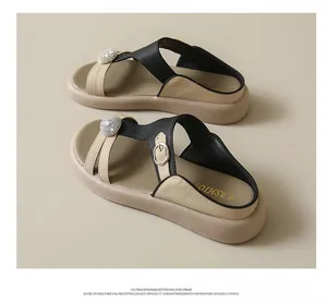 Detailansicht der beigen und schwarzen Plateausandalen mit glitzerndem Strassakzent.