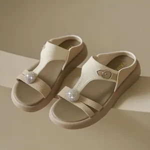 Nahaufnahme von eleganten beigefarbenen Plateausandalen mit Strasssteinen und weichen Sohlen.