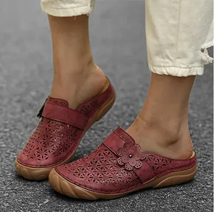 Close-up detail of wine red hollow-out floral clogs with thick soles on model feet in sun