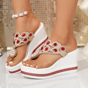 Close-up of white platform wedge flip-flops with red rhinestones and pearls.