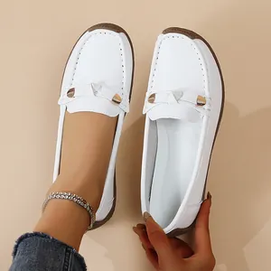 Detailed view of white soft-sole leather loafers with elegant metal buckle decoration