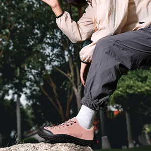 Detail view of wide-toe barefoot outdoor hiking shoes in pink on a rock