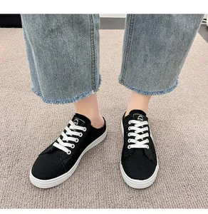 Primer plano de zapatillas tipo mule de lona negra combinadas con vaqueros azules