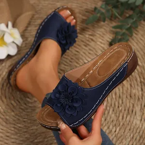 Primer plano de sandalias de cuña azul marino con adorno floral y costuras blancas