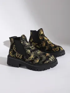 Vista detallada de los botines Chelsea negros para mujer con estampados de mariposas doradas