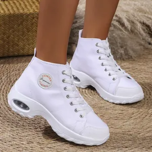 Close-up shot of women's white high-top platform canvas sneakers on a woven mat