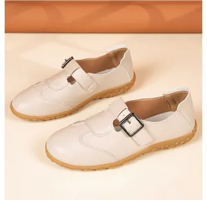 Nahaufnahme von beigen Vintage-Slippern mit verstellbarer Schnalle und Gummisohle.