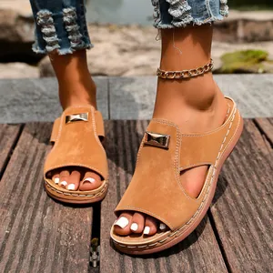 Gros plan de sandales compensées en daim beige pour femmes avec boucle en métal doré