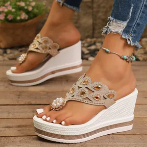 Primer plano de chanclas de cuña elegantes con detalles de pedrería y perlas blancas