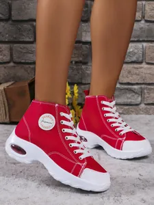 Macro detail view of red high-top canvas sneakers featuring white laces and air cushion sole.