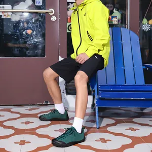 Detailed side view of green wide-toe barefoot outdoor shoes worn by male model on street