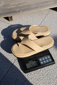 Medición detallada del peso de las sandalias chanclas beige con plataforma en una báscula