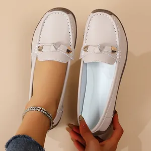 Detailed view of cream slip-on loafers featuring soft sole and gold buckle