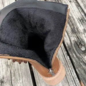 Detailopname van de warme zwarte voering van imitatiebont in deze bruine dameslaarzen.