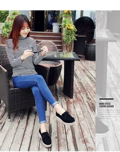 Elegantes mocasines negros con plataforma y borlas usados por modelo en patio exterior.