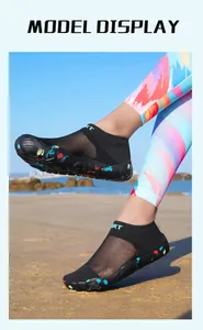 Close-up of black five-finger aqua shoes with colorful soles on a sandy beach