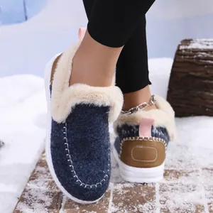 Close-up of blue winter slippers with white faux fur lining and stitching details on snow.
