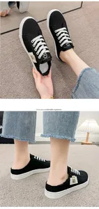 Detalle de las elegantes zapatillas mule de lona negra con cordones y suelas blancas duraderas