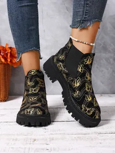 Vista detallada de botas Chelsea para mujer con estampado de mariposas doradas y suela gruesa