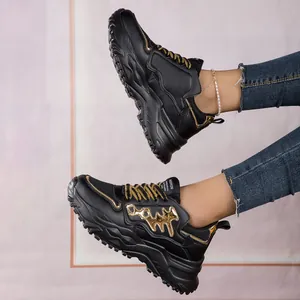 Detailed view of women's black and gold fishbone chunky sneakers worn with denim jeans