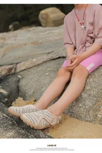Child wearing breathable zebra print mesh water shoes on a rocky beach shore outdoors