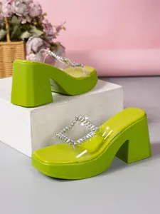 Detail of lime green platform mules with rhinestone buckle and clear PVC strap