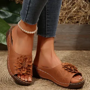 Primer plano de sandalias marrones con cuña, flores decorativas y costuras.