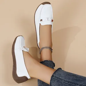 White leather loafers on feet with denim jeans, showcasing soft flat soles.