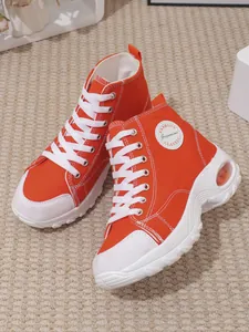 Side view of vibrant orange high-top canvas platform sneakers with white laces.
