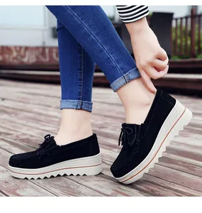 Primer plano de mocasines de plataforma en ante negro con borlas decorativas elegantes