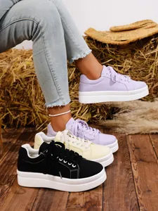 Detalle de zapatillas de lona con suela gruesa en color púrpura, crema y negro
