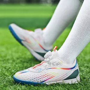 Kids' white turf soccer shoes with rotary buckle and rainbow colors on grass field