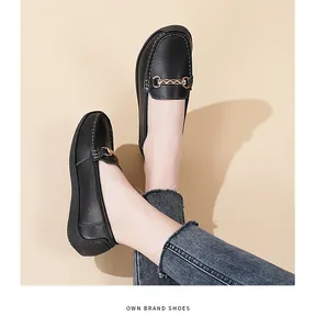Detailed view of comfortable black leather loafers with gold chain worn by model in studio