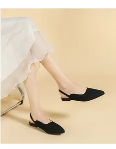Elegant black knitted pointed-toe slingback flat sandals shown on a model's feet
