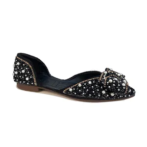Detailweergave van elegante zwarte puntige ballerina's met strik, stras en parels.