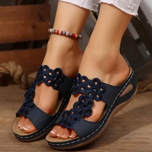 Dettaglio di sandali con zeppa blu navy con intagli floreali e cuciture bianche.