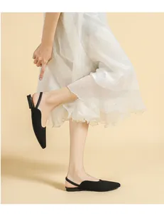 Close-up detail of stylish black knitted pointed-toe slingback flat sandals on a model