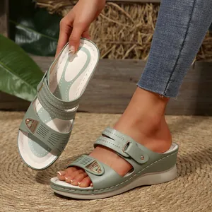 Close-up of sage green wedge sandals featuring gold buckles and decorative stitching