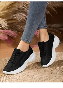 Detail view of black platform dad shoes with breathable mesh and thick white sole on model.