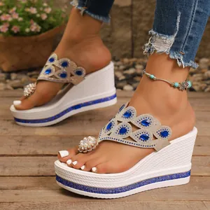 Primer plano de sandalias con cuña blancas con pedrería azul y detalles de perlas