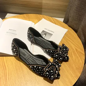 Detailweergave van zwarte puntige ballerina's met parels, strass en strik