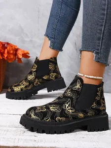 Vista detallada de botines Chelsea negros con elegantes estampados de mariposas en la modelo