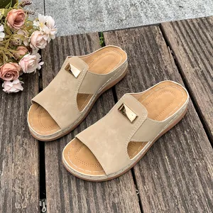 Sandales à talons compensés beiges pour femmes avec boucle dorée sur un fond en bois