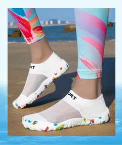 Close-up view of white mesh barefoot water shoes worn on a sandy beach