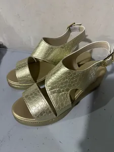 Vue détaillée de sandales compensées dorées avec brides à motif crocodile texturé élégantes