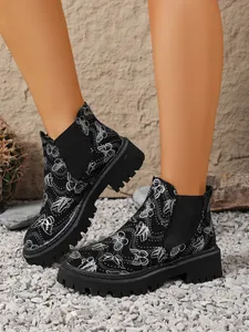 Vista detallada de botines Chelsea negros con estampado de mariposas y suela dentada