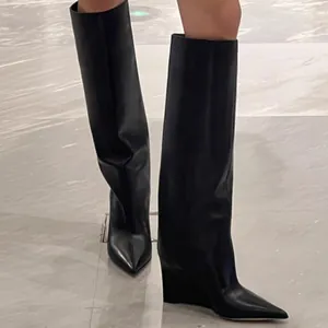 Detailed side view of black pointed-toe wedge knee-high boots with straight shaft