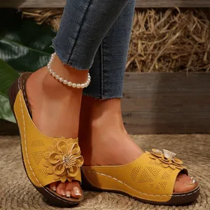 Primer plano de sandalias de cuña amarillas con flores y tobillera de perlas