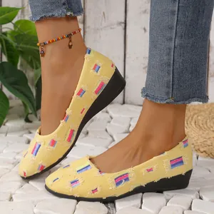 Detalle de mocasines de lona amarilla con parches coloridos y una cómoda suela de cuña